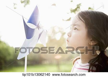 Stock Image - a girl playing with a toy wind mill. Fotosearch