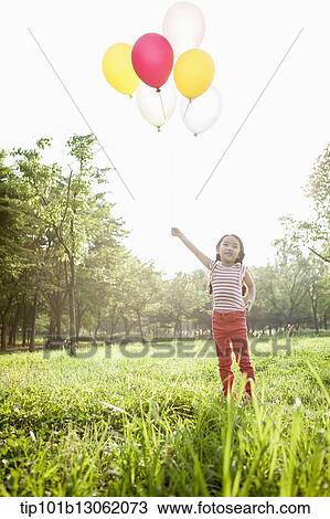 Stock Image - a girl playing with balloons. Fotosearch