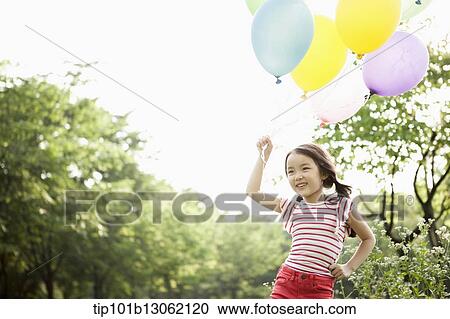Stock Image - a girl playing with balloons. Fotosearch