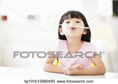 Stock Image - a girl playing with pencil. Fotosearch