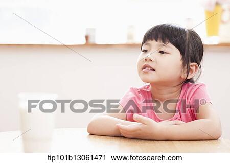 Stock Image - a girl sitting at a table smiling. Fotosearch