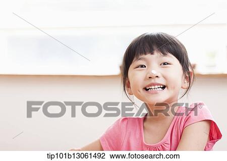 Stock Image - a girl sitting at a table smiling. Fotosearch