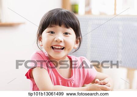 a girl sitting at a table smiling View Large Photo Image Stock Photo - a girl sitting at a table smiling. Fotosearch
