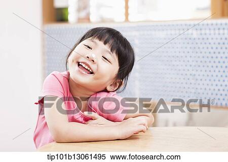 a girl sitting at a table smiling View Large Photo Image Stock Photography - a girl sitting at a table smiling. Fotosearch