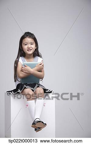a girl sitting on a box hugging a book View Large Photo Image Stock Image - a girl sitting on a box hugging a book. Fotosearch