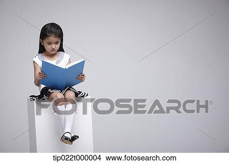 Picture - a girl sitting on a box reading a book. Fotosearch