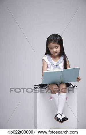 a girl sitting on a box reading a book View Large Photo Image Stock Photo - a girl sitting on a box reading a book. Fotosearch