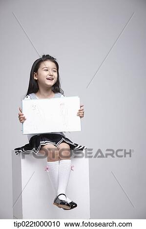 a girl sitting on a box showing a book View Large Photo Image Stock Image - a girl sitting on a box showing a book. Fotosearch