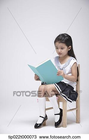 a girl sitting on a chair reading a book View Large Photo Image Stock Image - a girl sitting on a chair reading a book. Fotosearch