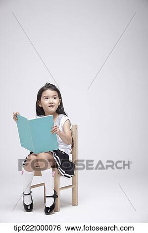 a girl sitting on a chair reading a book View Large Photo Image Stock Photograph - a girl sitting on a chair reading a book. Fotosearch