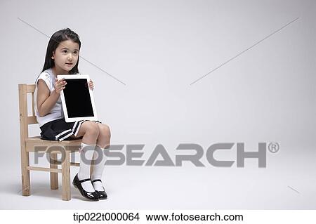 a girl using tablet PC on a chair View Large Photo Image Picture - a girl using tablet PC on a chair. Fotosearch