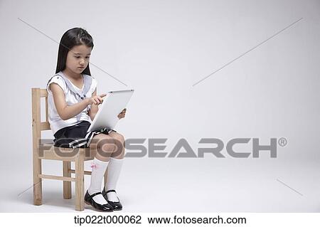a girl using tablet PC on a chair View Large Photo Image Stock Image - a girl using tablet PC on a chair. Fotosearch