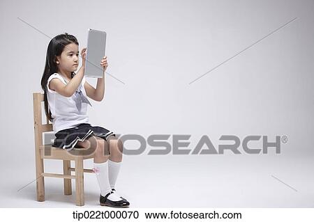 a girl using tablet PC on a chair View Large Photo Image Stock Image - a girl using tablet PC on a chair. Fotosearch