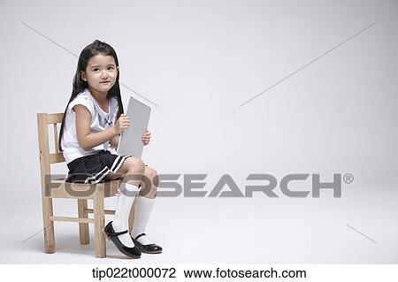 a girl using tablet PC on a chair View Large Photo Image Stock Image - a girl using tablet PC on a chair. Fotosearch