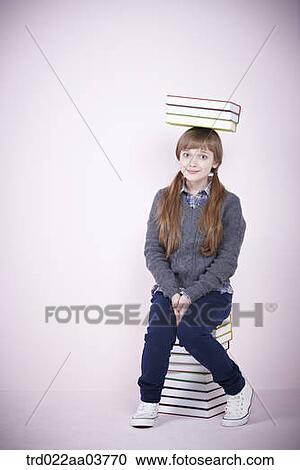 a girl with a pile of books sitting on a pile of books View Large Photo Image Stock Image - a girl with a pile of books sitting on a pile of books. Fotosearch