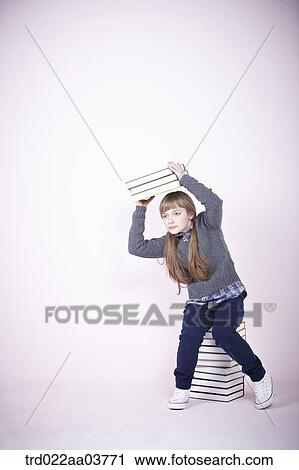 a girl with a pile of books sitting on a pile of books View Large Photo Image Stock Image - a girl with a pile of books sitting on a pile of books. Fotosearch