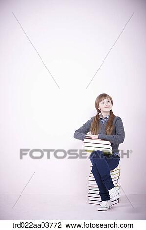a girl with a pile of books sitting on a pile of books View Large Photo Image Stock Image - a girl with a pile of books sitting on a pile of books. Fotosearch