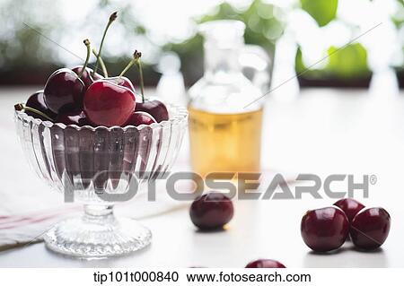 Stock Image - a glass with cherries next to a pot of juice. Fotosearch