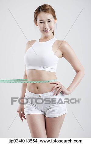 Picture - a healthy looking woman with measurement tape around the waist. Fotosearch