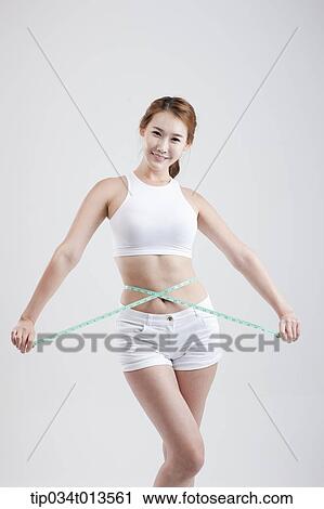 Stock Image - a healthy looking woman with measurement tape around the body. Fotosearch