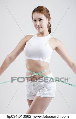Stock Image - a healthy looking woman with measurement tape around the body. Fotosearch