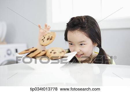 Stock Photo - a kid peeking cookies in the kitchen. Fotosearch