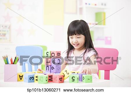 Stock Image - a kid playing with toy cubes on a table. Fotosearch