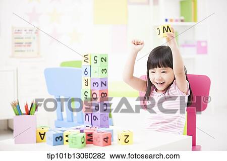 Stock Image - a kid playing with toy cubes on a table. Fotosearch
