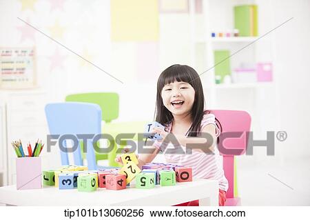 Stock Photograph - a kid playing with toy cubes on a table. Fotosearch