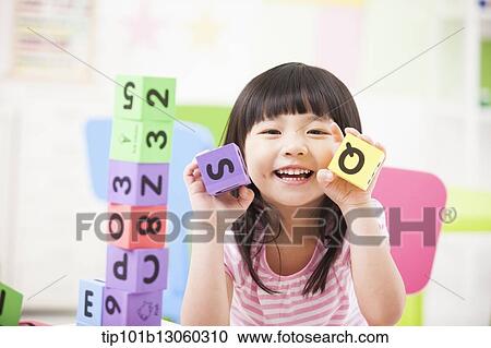 Stock Image - a kid playing with toy cubes. Fotosearch