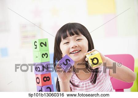 Stock Photograph - a kid playing with toy cubes. Fotosearch