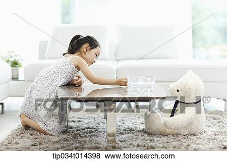 Stock Photo - a kid with a teddy bear on the other end of table. Fotosearch