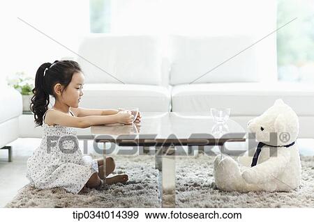 Stock Photo - a kid with a teddy bear on the other end of table. Fotosearch