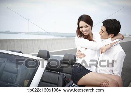 Picture - a man and a woman in a convertible car. Fotosearch
