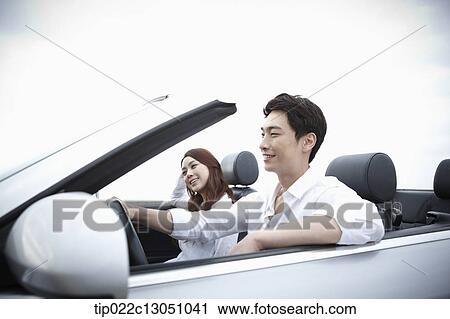 Stock Image - a man and a woman in a convertible car. Fotosearch
