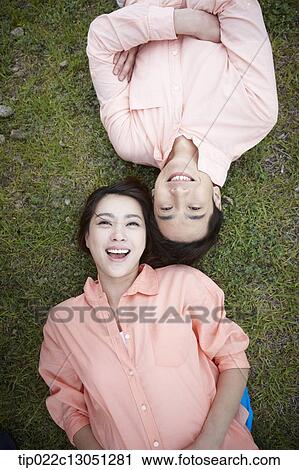 Stock Image - a man and a woman lying on a grass field. Fotosearch