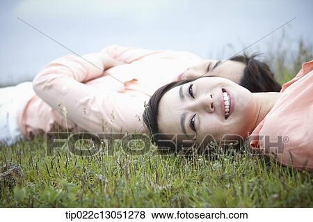 Stock Photo - a man and a woman lying on a grass field. Fotosearch