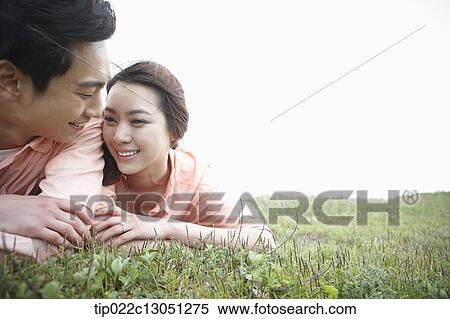 Stock Photography - a man and a woman lying on a grass field. Fotosearch