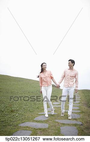 Stock Photo - a man and a woman on a road on a grass field. Fotosearch