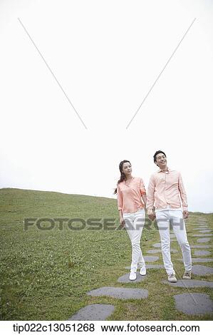 Stock Photo - a man and a woman on a road on a grass field. Fotosearch