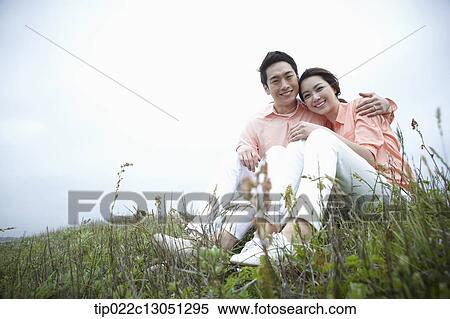 a man and a woman sitting on a grass field View Large Photo Image Stock Photography - a man and a woman sitting on a grass field. Fotosearch