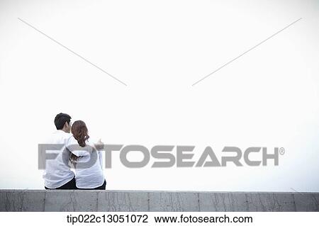 Stock Image - a man and a woman sitting on an edge. Fotosearch