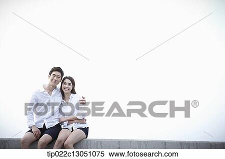 Stock Photography - a man and a woman sitting on an edge. Fotosearch