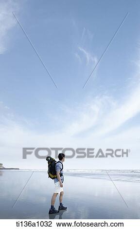 Stock Image - a man hiking on a beach. Fotosearch