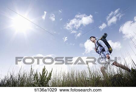 a man hiking on a grass field View Large Photo Image Stock Photo - a man hiking on a grass field. Fotosearch
