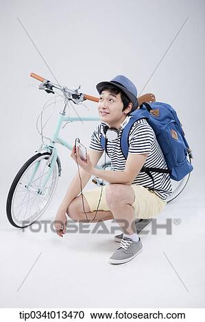 Stock Image - a man listening to music next to a bike. Fotosearch