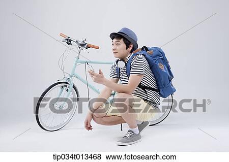 Stock Photo - a man listening to music next to a bike. Fotosearch