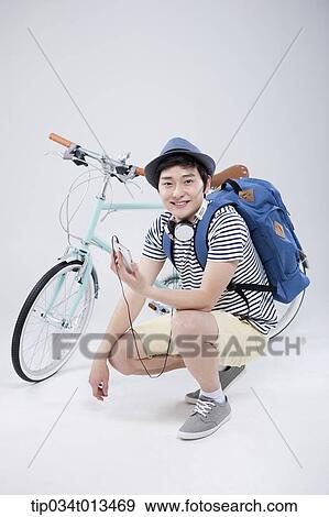 Stock Photo - a man listening to music next to a bike. Fotosearch