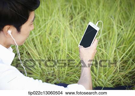 a man sitting on the grass listening to music View Large Photo Image Picture - a man sitting on the grass listening to music. Fotosearch