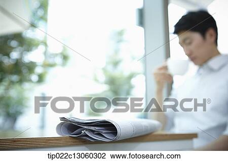 Stock Image - a man with a white shirt behind a newspaper. Fotosearch